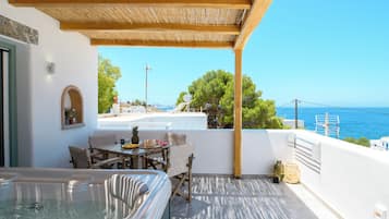 Eine Dachterrasse mit Whirlpool, Essbereich und Meerblick.