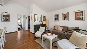 En moderne stue med sofa, stole, spisebord og billedkunst på væggene.