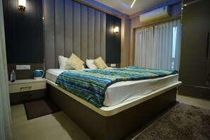 Un dormitorio moderno con una cama grande, mesitas de noche, una lámpara de noche, una botella de agua y un hervidor.