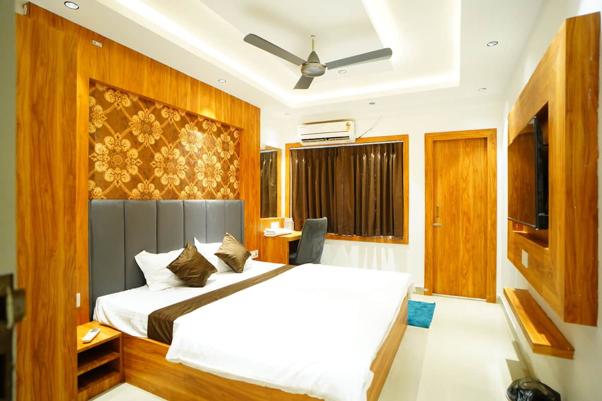 Une chambre d’hôtel moderne équipée d’un grand lit, d’un bureau, d’une chaise, d’un ventilateur de plafond, d’un climatiseur et d’un téléviseur fixé au mur.
