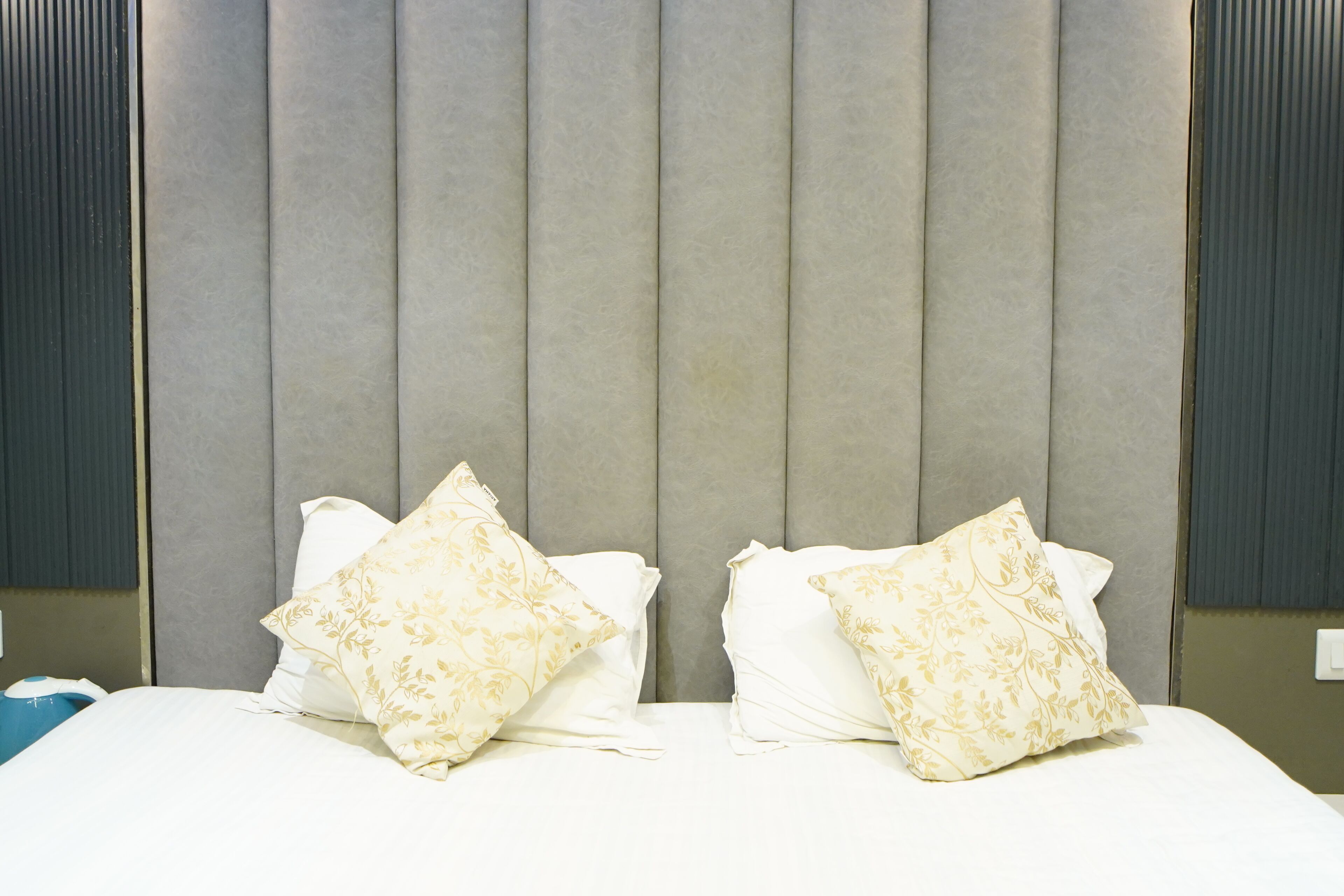 Una habitación de hotel con una cama grande, dos almohadas decorativas y un cabecero acolchado.