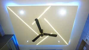 Un soffitto con una lampada moderna e una ventola a soffitto.