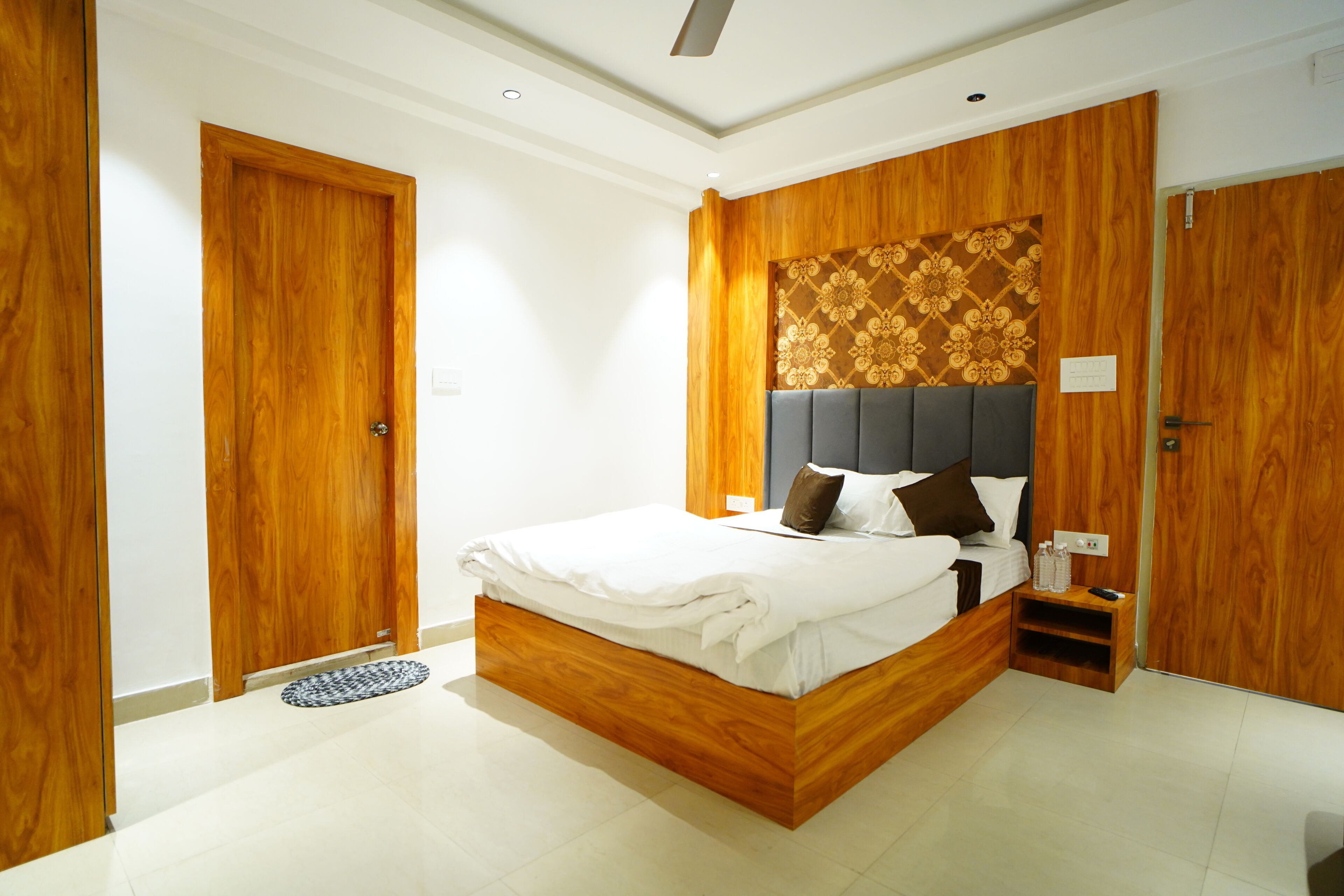 Un dormitorio moderno con estructura de cama de madera, cabecera con diseño estampado y mesita de noche con control remoto.