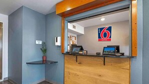 A hotel reception area with a wooden reception desk, a potted plant, and a sign indicating 6 suites. - 2 Full Beds | Non-Smoking, Kitchen (Cincinnati OH)