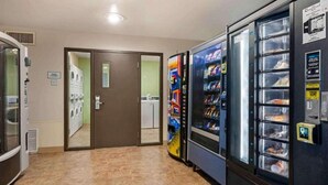 A hotel corridor with a guest laundry area, vending machines, and a door leading to another room. - 2 Full Beds | Non-Smoking, Kitchen (Cincinnati OH)