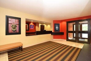 Un hall de hotel con una recepción, un banco y obras de arte enmarcadas en las paredes.