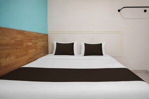 A bed with a wooden headboard, white bedding, and two black pillows. - Hotel O near Bunda Thamrin Hospital  (Medan)
