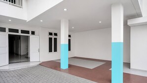 A spacious indoor area with white walls, large columns, and a tiled floor.