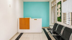 Ein Empfangsbereich mit einer türkisblauen Wand, einem Holzbüro und schwarzen Stühlen.