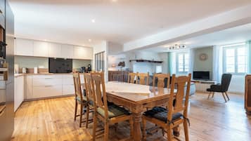 A spacious kitchen with modern appliances, a dining area with wooden chairs, and a living room with a television and seating.