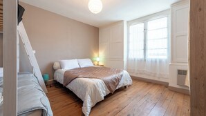 Une chambre à coucher avec un lit, une table de chevet, une lampe et une fenêtre.