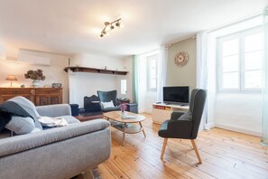 Una sala de estar moderna con sofá, sillón, mesa de centro, televisor y suelo de madera.