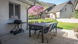 Une terrasse extérieure avec une table et des chaises, un barbecue et une vue sur une montagne.