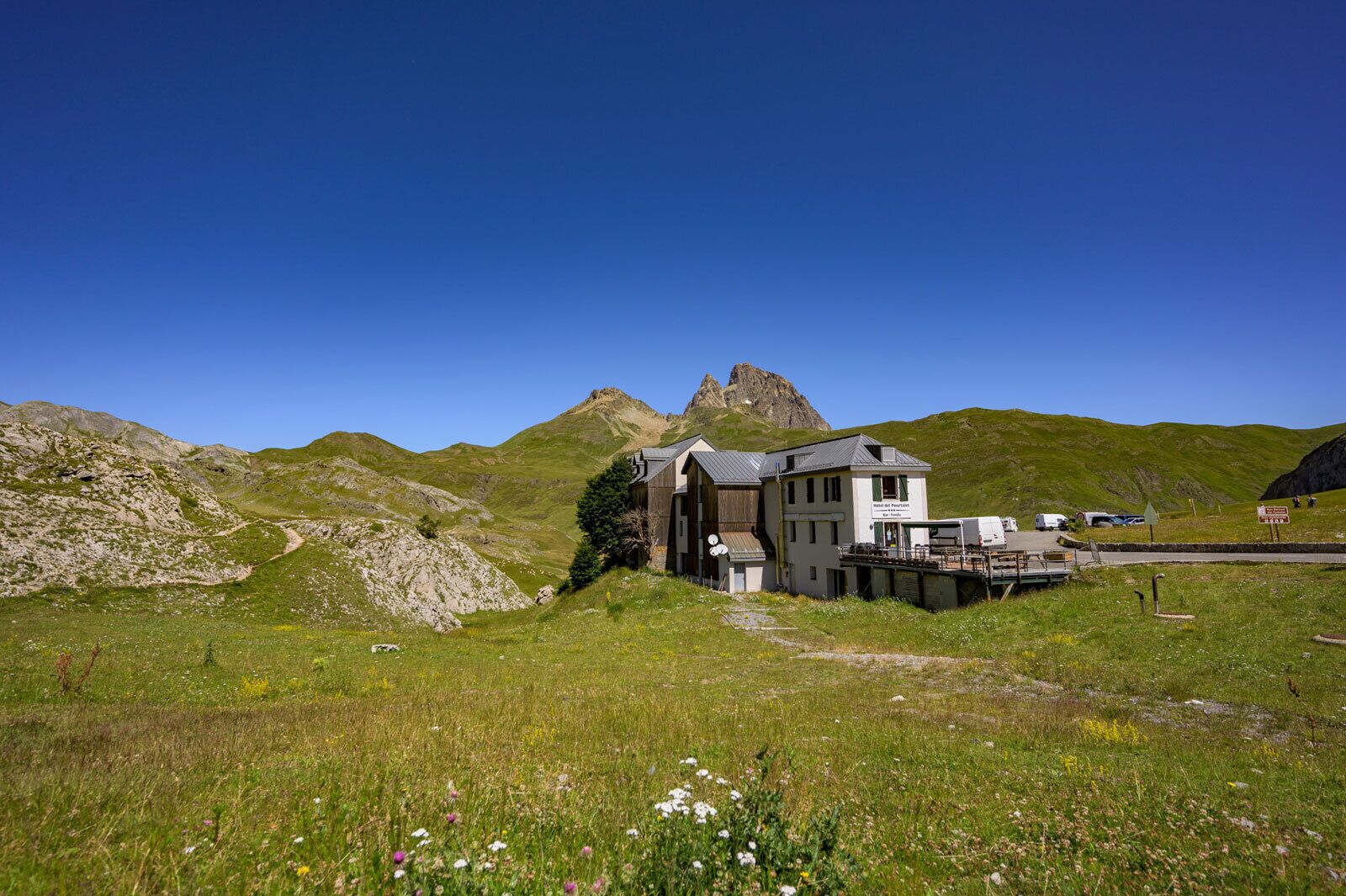 A mountain lodge with a wooden exterior, a deck, and a view of a mountain peak.