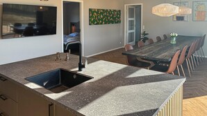 A kitchen with a sink, a dining area with a wooden table and chairs, and a hallway with a bed and a door. - Pet friendly home in Børkop with sauna (Børkop)