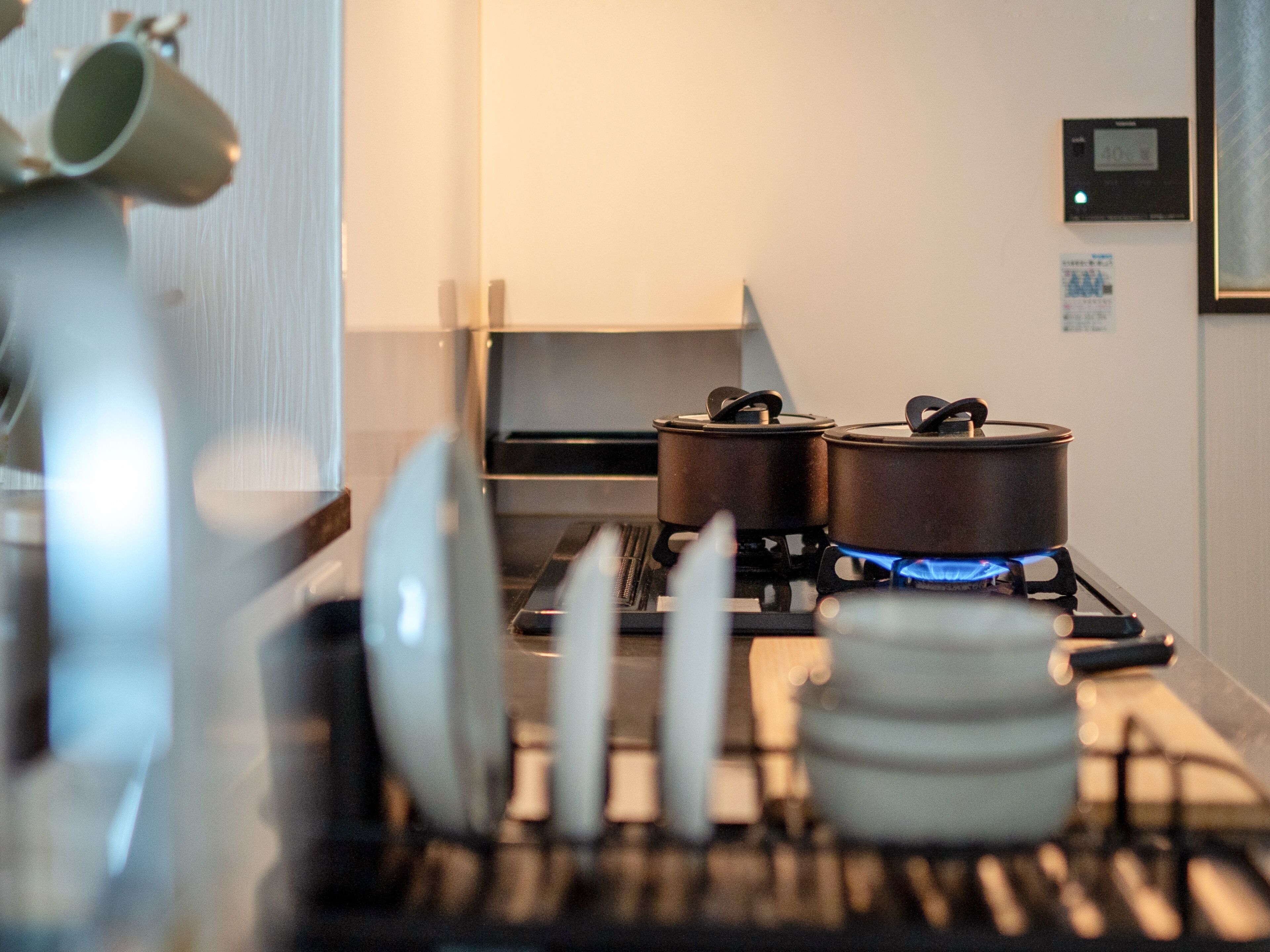 A kitchen with a gas stove, pots, and a coffee machine.