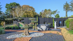 A modern building with a minimalist design, surrounded by a landscaped garden with various plants and a gravel pathway. - Egret - La Laïta (Guidel)