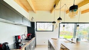 A modern kitchen with wooden ceiling beams, a large window, and a bar area. - Egret - La Laïta (Guidel)