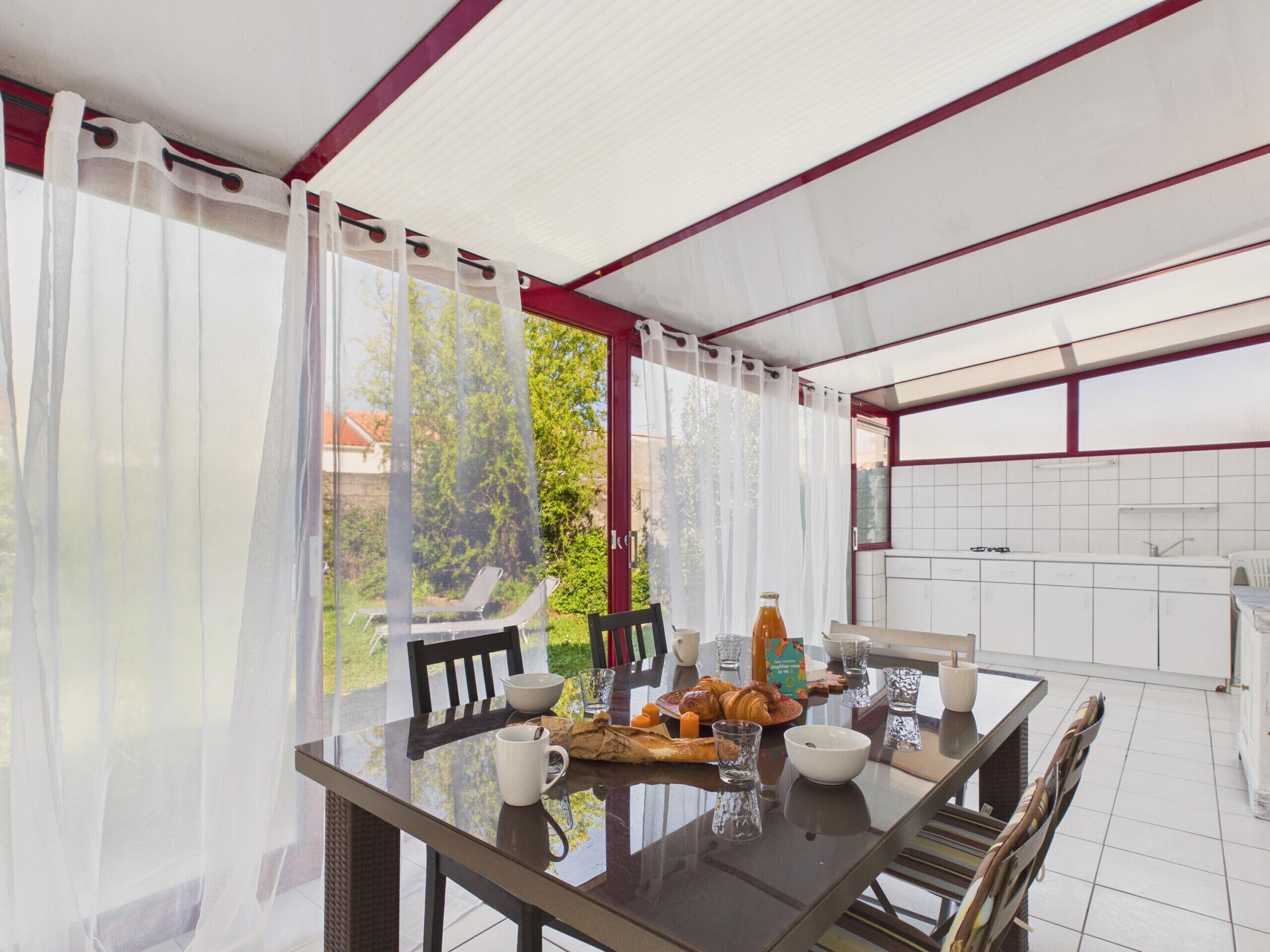 A dining area with a table set for breakfast, including croissants, a bottle, and bowls.