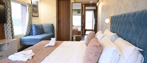 A hotel room with a bed, a sofa, a TV, a window with curtains, and a mirror.