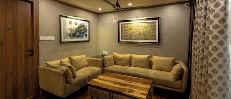 A living room with a sectional sofa, a wooden coffee table, and two framed artworks on the walls.