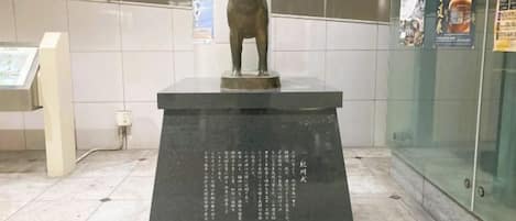 A statue of a dog on a pedestal with engraved text.
