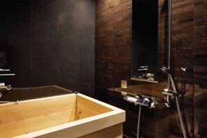 Un baño moderno con una bañera de madera, un espejo grande y una pared elegante en tono oscuro.