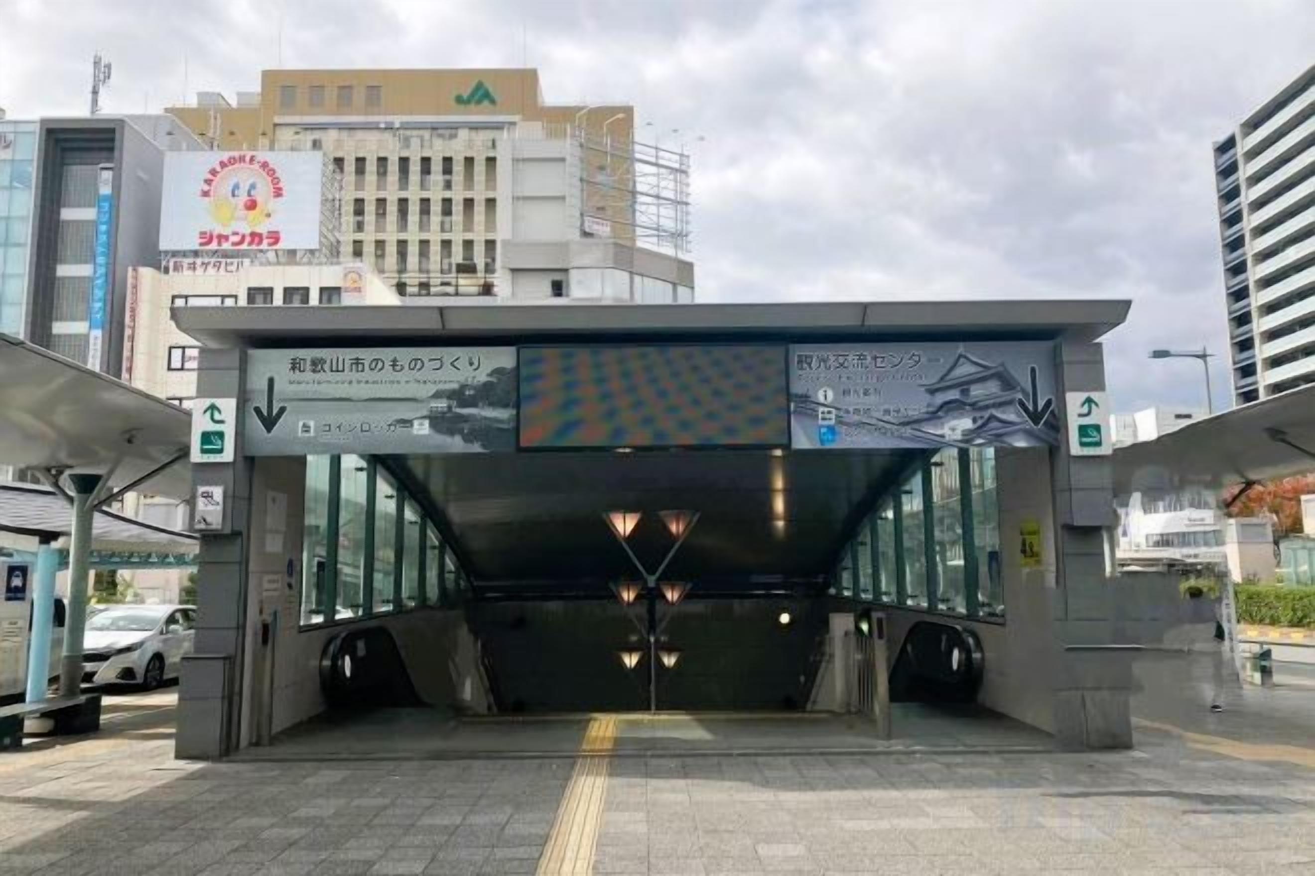 A modern train station entrance with clear signage, a covered waiting area, and a visible platform.