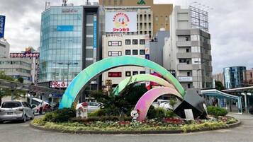 A roundabout with colorful arches and a panda statue, surrounded by buildings and cars.