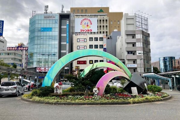Uma rotatória com arcos coloridos e uma estátua de panda, cercada por edifícios e carros.