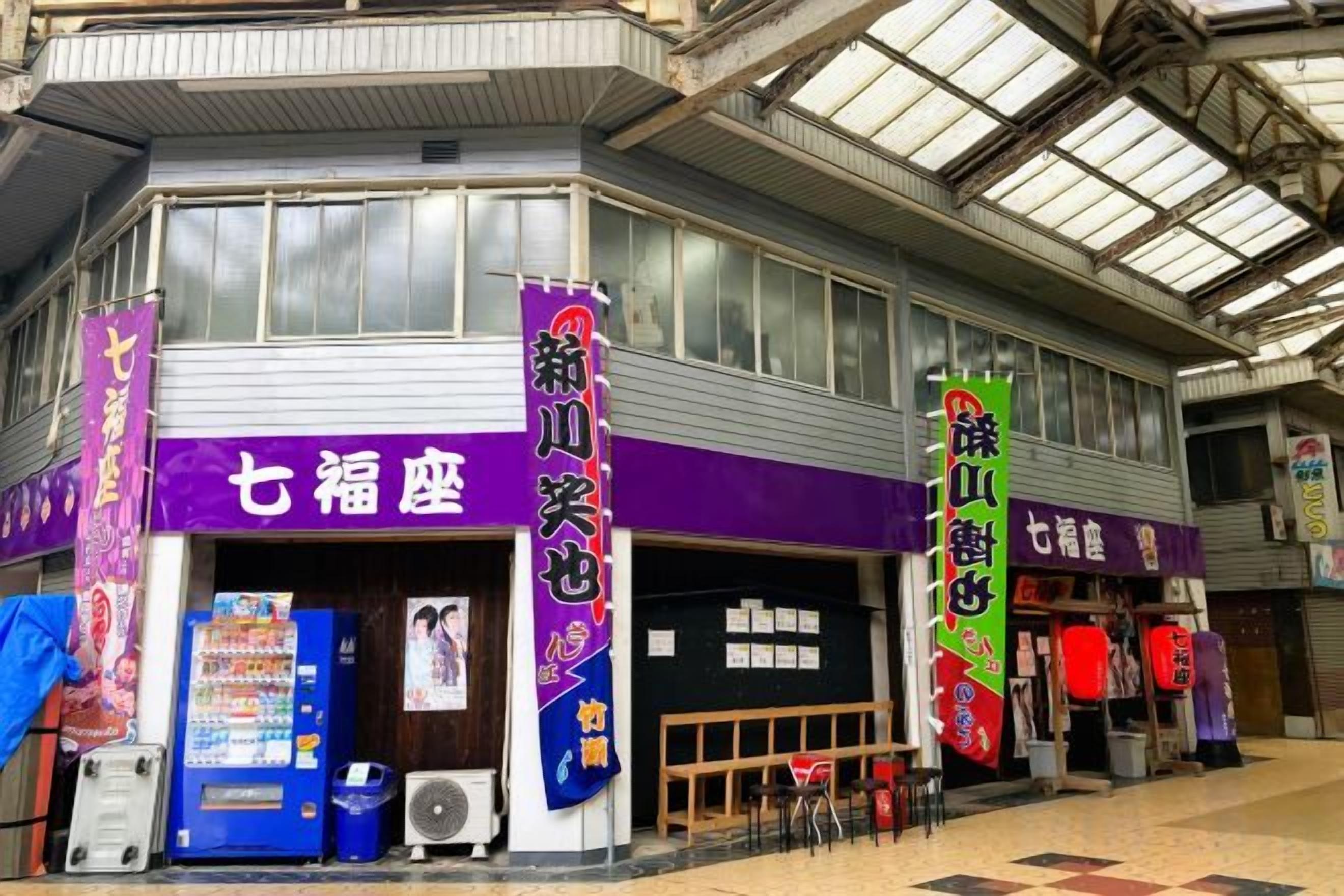 A commercial building with a purple storefront, vending machines, and a covered entrance.