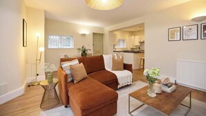 A living room with a brown sofa, a round coffee table, a floor lamp, and a hanging light fixture. - The Tufnell Threshold (London)