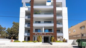 A multi-story building with a prominent entrance labeled 'PLUS 11 by GC'. - Kmeidos 1-BR Apt & Balcony in Larnaca (Larnaca)