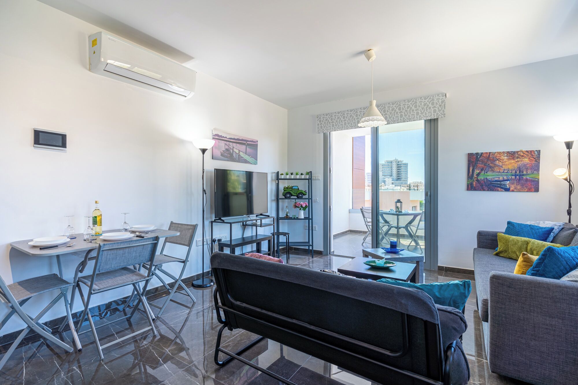 A modern living room with a sofa, a dining table with chairs, a TV, and a balcony with a view.