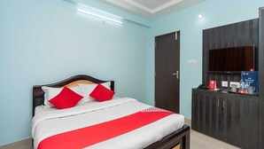 Habitación de hotel con cama, armario, televisor y ventilador de techo.