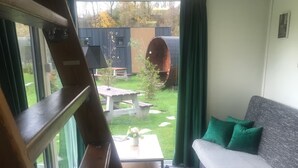 Een woonkamer met een bank, een salontafel en uitzicht op de achtertuin.