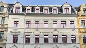 A row of multi-story buildings with uniform window designs and red doors. - Compact city apartment for 2 people (GÖ02) (Görlitz)