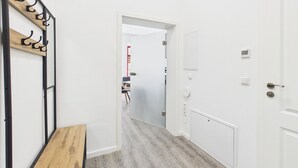 A hallway with a wooden bench, a coat rack, a door with a thermostat, and a view into another room. - Compact city apartment for 2 people (GÖ02) (Görlitz)