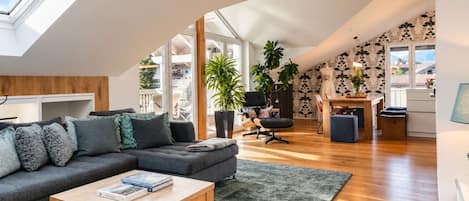 Un loft moderno con un tragaluz grande, una zona de estar acogedora, un comedor y vistas al exterior.
