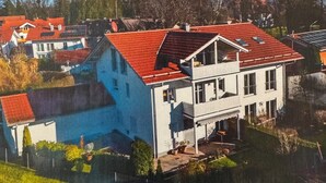 Ein zweistöckiges Haus mit rotem Dach, einem Balkon und einem kleinen Garten.