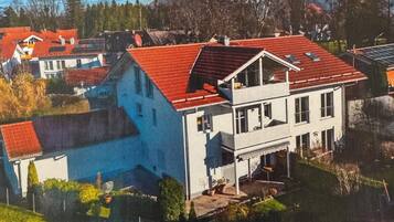 Ein zweistöckiges Haus mit rotem Dach, einem Balkon und einem kleinen Garten.
