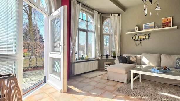 An open living area with a sofa, coffee table, and a view of the outdoors. - Vacation apartment S22 - Holiday apartment S22 with terrace and WLAN in Graal-Müritz (Graal-Müritz)