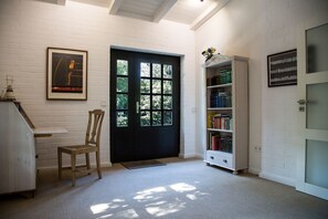 A room with a black door, a bookshelf, a framed picture, and a chair. - Vacation home Reidschott - Holiday home Reidschott - modern, cozy and (Wyk auf Föhr)