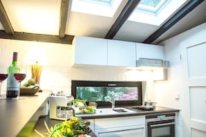 A modern kitchen with a skylight, a built-in stove, and a window with a view of greenery. - Vacation home Reidschott - Holiday home Reidschott - modern, cozy and (Wyk auf Föhr)