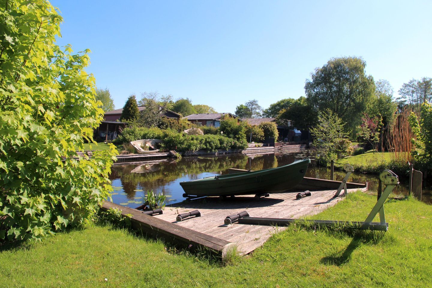 A calm water body with a dock, boats, and greenery.