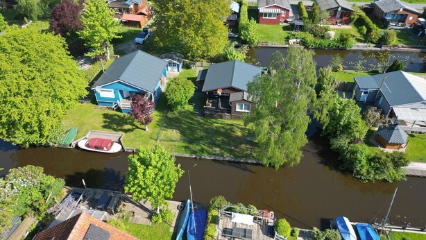 A residential area with houses, a dock, and a body of water. - Möwenglück am Meer - Holiday home Möwenglück am Meer with garden by the water (Südbrookmerland)
