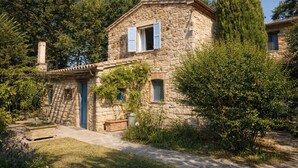 A stone house with a small garden, a stone bench, and a tall tree. - I escape to Umbria, Torreluca (todi)