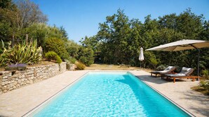 A rectangular swimming pool with a stone wall on one side and lounge chairs with umbrellas on the other. - I escape to Umbria, Torreluca (todi)