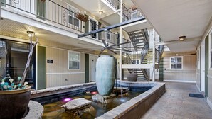 A multi-level indoor courtyard with a central water feature, stone steps, and a staircase. - Stylish 1BR on Frenchmen Street with king bed, hot tub, garden courtyard, and easy walk to the French Quarter. (New Orleans)