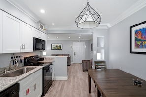 A modern kitchen with white cabinetry, a built-in oven, and a granite countertop.